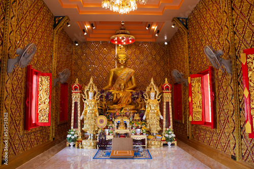 Ancient golden buddha statue in antique ubosot for thai people travelers travel visit and respect praying blessing to holy mystery worship at Wat Maniwong or Mani Wong temple in Nakhon Nayok, Thailand photo