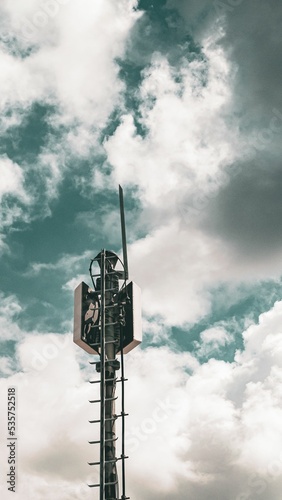 Fotografie Vertical shot of a cell tower against a cloudy sky background