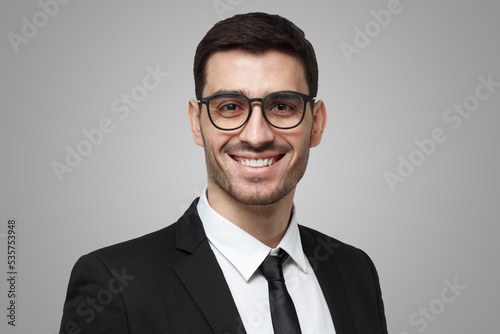 Man in formal clothes looking through glasses and smiling, feeling confident about business success
