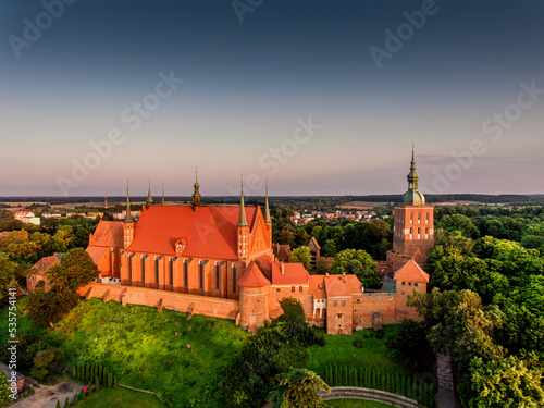 Great view of the beautiful city of Frombork located in Warmia, Poland. Cathedral Hill among trees at sunset.