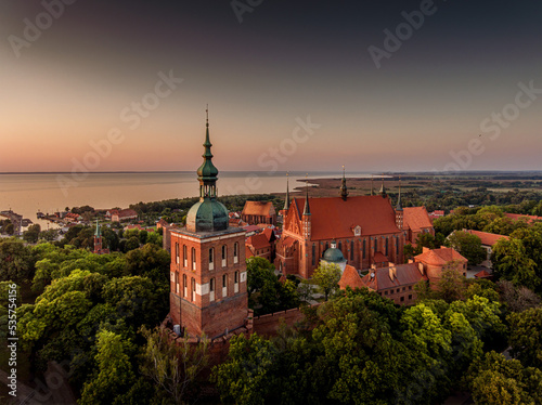 Great view of the beautiful city of Frombork located in Warmia, Poland. Cathedral Hill among trees at sunset.