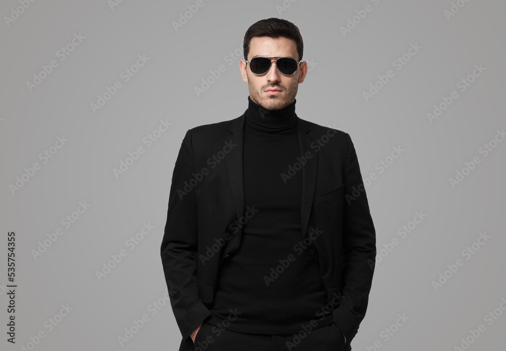 Obraz premium Guy in total black with turtleneck, sunglasses and jacket, looking serious, suspicious and reserved