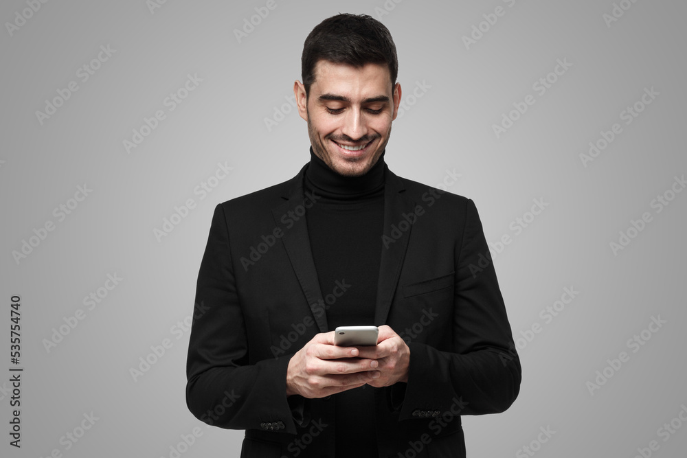 Young business man looking attentively at phone screen, browsing web pages and smiling chatting Young business man looking attentively at phone screen, browsing web pages and smiling chatting