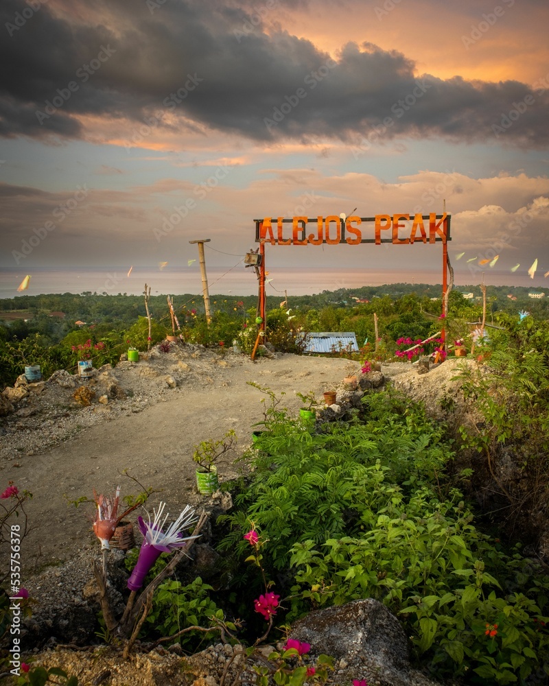 Obraz premium Scenic view of Alejo's Peak park with a sign in Bogo, Cebu, Philippines, at sunset