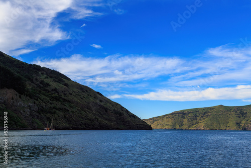 The headlands at the entrance to Akaroa Harbour, South Island, New Zealand. A sailboat is just visible to the left