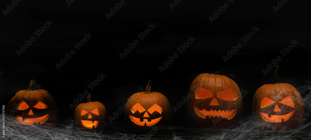 Scary Halloween celebration holiday card - Many spooky carved pumpkins and spider webs on dark wooden wall background banner panorama. Scary Halloween celebration holiday card - Many spooky carved pumpkins and spider webs on dark wooden wall background banner panorama.