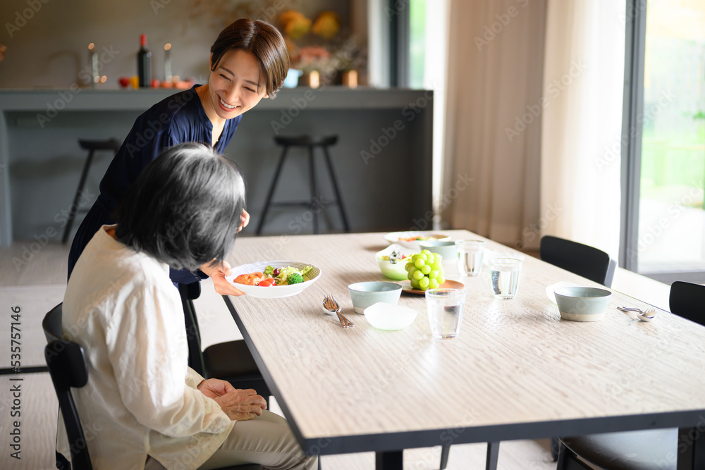 Woman serving food to grandmother in dining room Woman serving food to grandmother in dining room