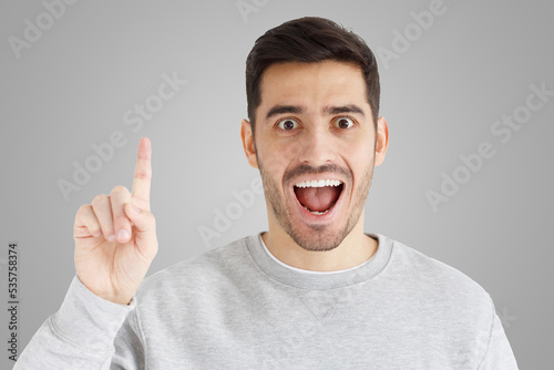 Portrait of excited man looking at camera, smiling, pointing finger up if he has great idea