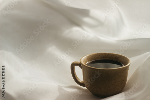 cup of coffee in the morning. espresso coffee. Coffee porridge on a white background a cup of coffee on a white cloth. sun rays on a cup of coffee