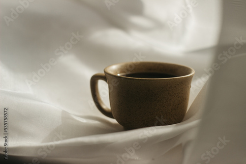 cup of coffee in the morning. espresso coffee. Coffee porridge on a white background a cup of coffee on a white cloth. sun rays on a cup of coffee