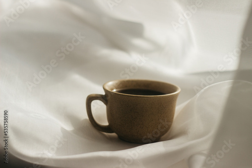 cup of coffee in the morning. espresso coffee. Coffee porridge on a white background a cup of coffee on a white cloth. sun rays on a cup of coffee