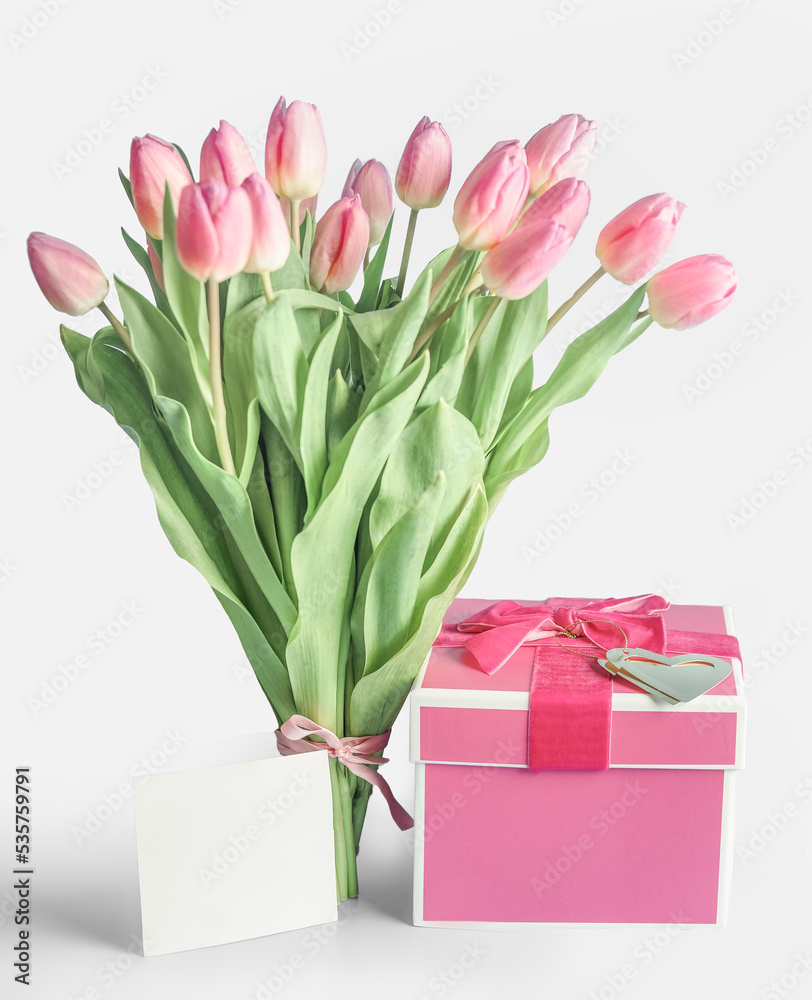 Fototapeta premium Lovely tulips bunch with pink gift box and blank greeting card at white background