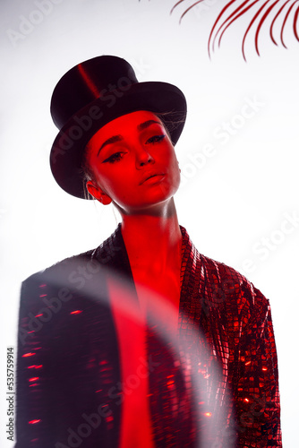 Front image of a sexy woman, with make-up wear in a glitter costume and top hat, isolated white background.
