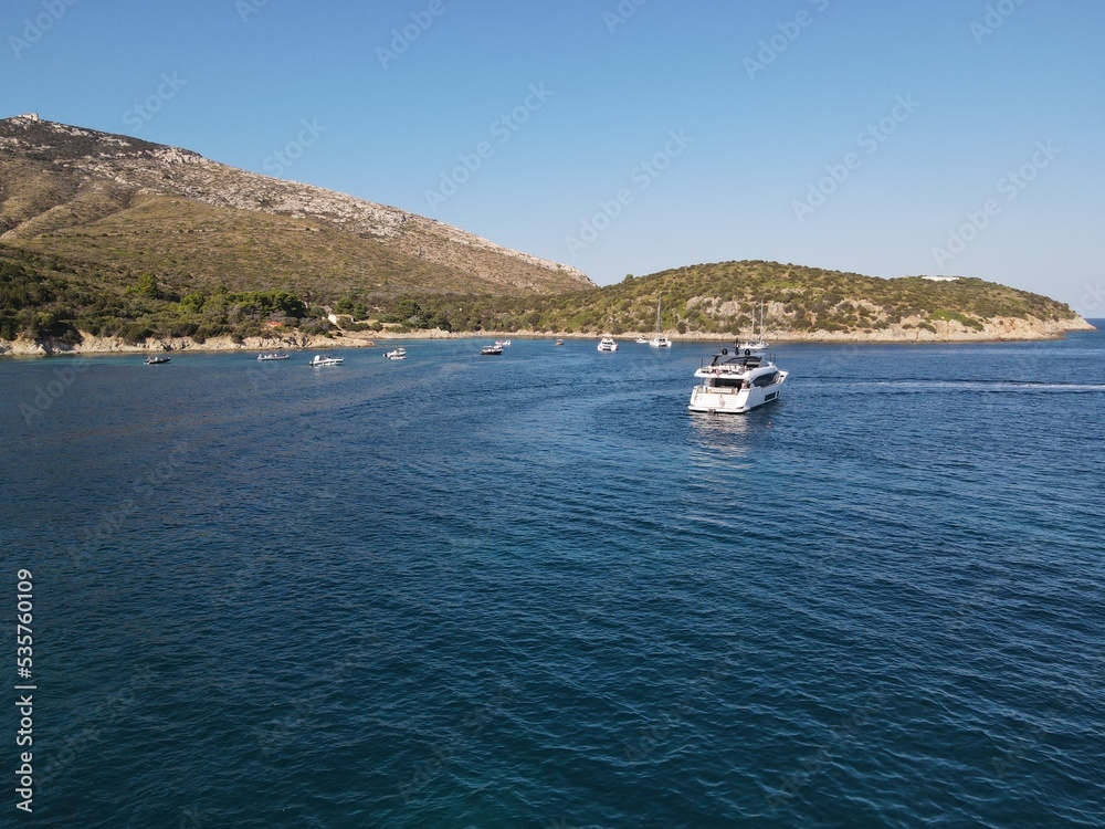 Aerial view of Cala Moresca and Figarolo Island in Golfo Aranci, north Sardinia. Birds eye from above of yacht, boats, crystalline and turquoise water. Tavolara Island in the background, Sardegna.