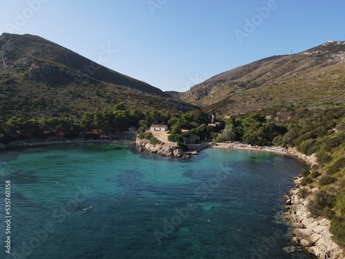 Aerial view of Cala Moresca and Figarolo Island in Golfo Aranci, north Sardinia. Birds eye from above of yacht, boats, crystalline and turquoise water. Tavolara Island in the background, Sardegna.