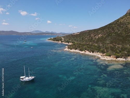 Aerial view of Cala Moresca and Figarolo Island in Golfo Aranci, north Sardinia. Birds eye from above of yacht, boats, crystalline and turquoise water. Tavolara Island in the background, Sardegna. © AerialDronePics