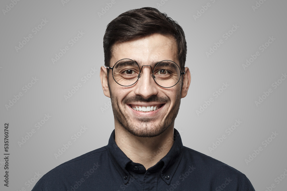 Smart businessman smiling at camera, wearing round glasses, isolated on gray Smart businessman smiling at camera, wearing round glasses, isolated on gray