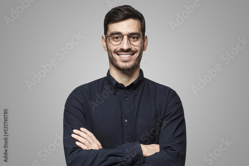 Portrait of male teacher smiling, wearing black shirt, isolated on gray background