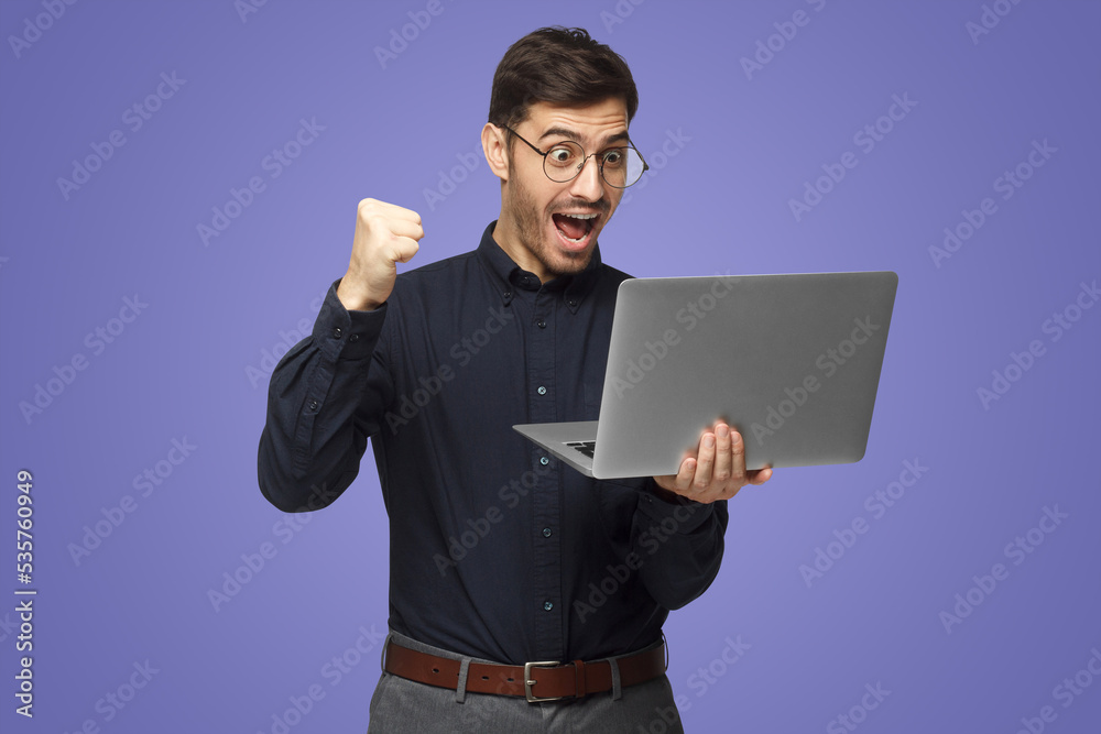 Excited business man looking at laptop screen with mouth wide open, celebrating his win Excited business man looking at laptop screen with mouth wide open, celebrating his win