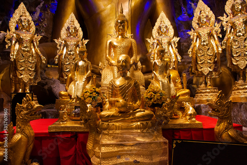 Golden buddha image statue and naga guardian of Wat Maniwong for thai people travel visit tunnel cave and respect praying blessing holy worship mystical at Mani Wong temple in Nakhon Nayok, Thailand photo
