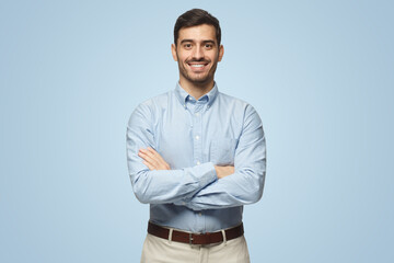 Modern business man in casual blue shirt standing with crossed arms on blue background