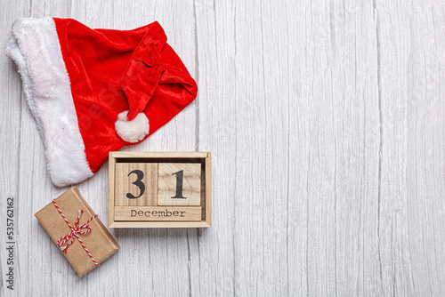 christmas hat, gift and wooden calendar 31 december on a wooden background