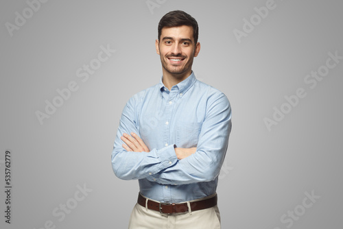 Handsome business man in blue shirt standing with crossed arms on gray background photo