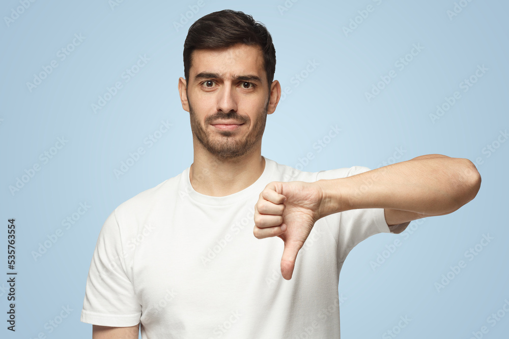 Man showing thumb down or dislike, isolated on blue background Man showing thumb down or dislike, isolated on blue background