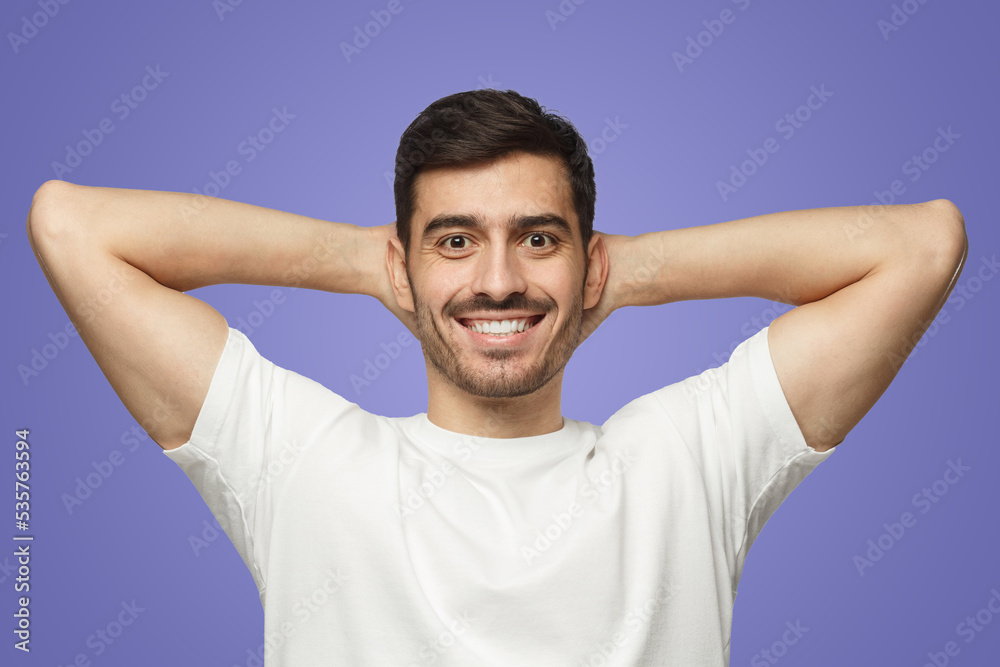 Man standing isolated on purple background with arms behind head, relaxing in free time Man standing isolated on purple background with arms behind head, relaxing in free time