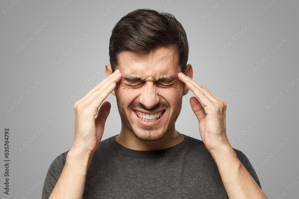 Man suffering from headache, pressing fingers to temples, closing eyes in order to relieve pain Man suffering from headache, pressing fingers to temples, closing eyes in order to relieve pain