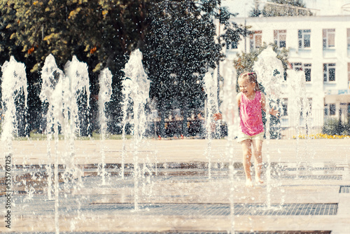 Fototapeta Naklejka Na Ścianę i Meble -  happy child playing with water splashes in city fountain