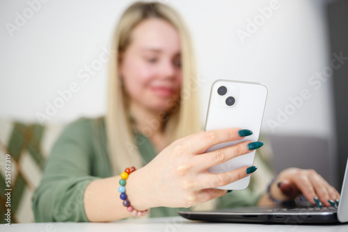 Young woman browsing mobile app on modern smartphone. Blonde female person using white mobile phone