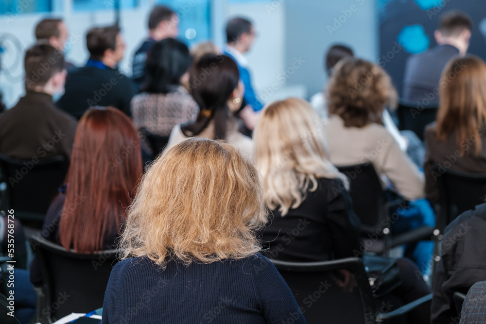 Woman in crowded auditorium during seminar Woman in crowded auditorium during seminar