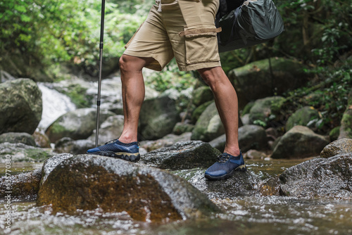 Canvas Print Close up legs of a trekker crossing river in the mountains