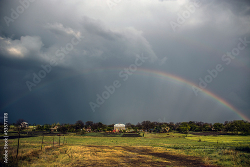 Big beautiful rainbow over the field and the village after the rain 