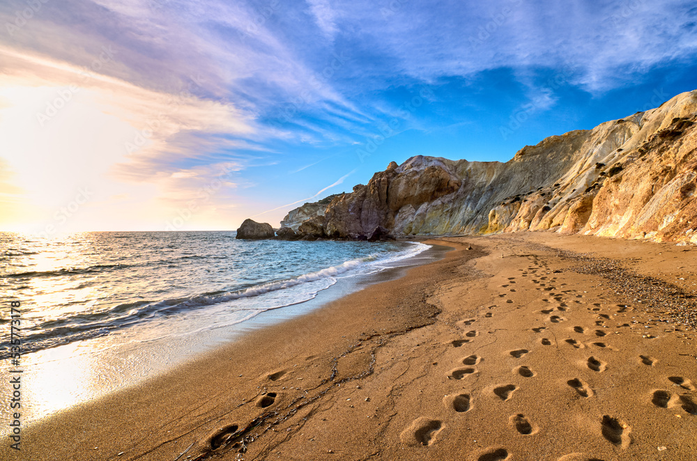 Low sun over beach, cliffs and hills and deep azure sea. Agios Ioannis