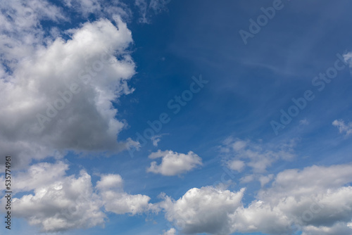 The wind blows fluffy white clouds in the blue sky