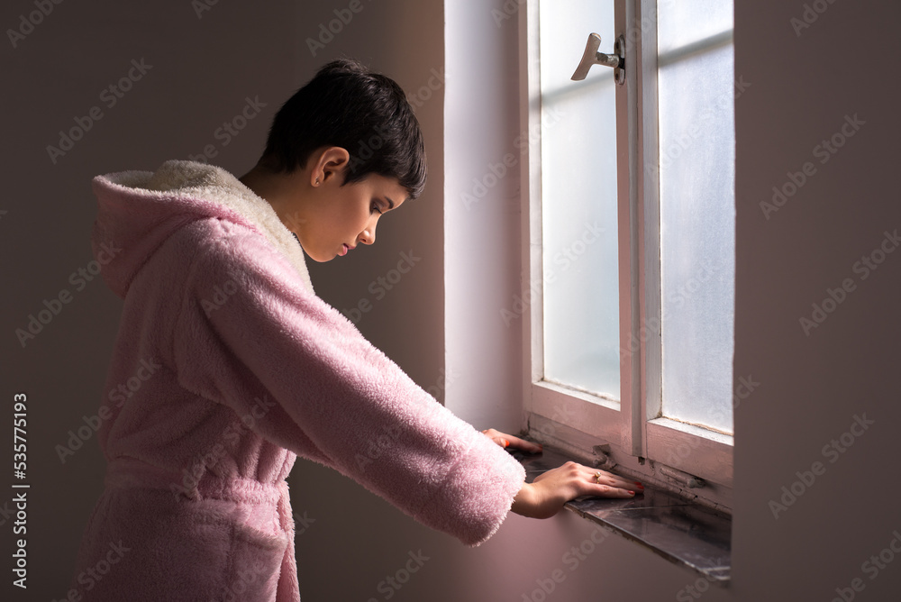 Young woman cancer patient standing in front of hospital window
