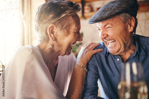 Senior, couple and laugh after comic joke together in restaurant for bonding time. Smile, man and woman in retirement laughing at funny conversation with love, happiness and comedy in cafe with wine photo