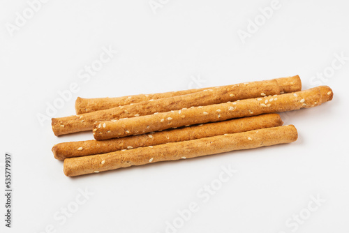 Pile of bread sticks grissini with sesame seeds in white form. Traditional Italian pastry breadsticks isolated  on white background
