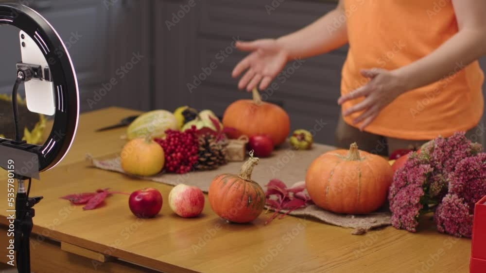 female blogger recording video using smartphone thanksgiving holiday decoration fall crop autumn ripe vegetables on kitchen table. woman live streaming mobile phone tripod circular led lamp pumpkins female blogger recording video using smartphone thanksgiving holiday decoration fall crop autumn ripe vegetables on kitchen table. woman live streaming mobile phone tripod circular led lamp pumpkins