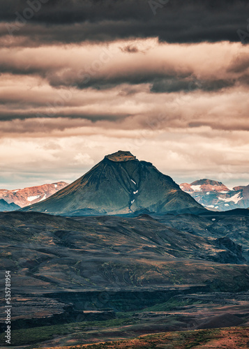 Volcano mountain on lava field and cloudy sky in Icelandic Highlands