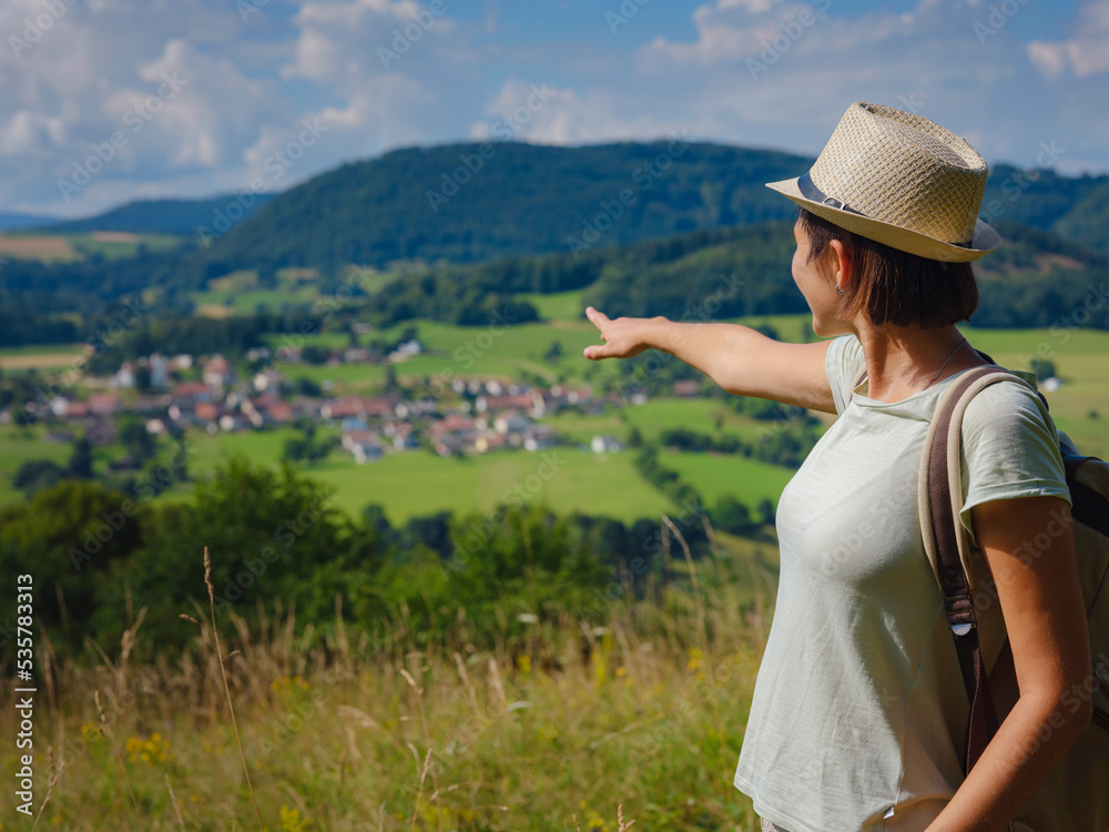 Fototapeta premium travel to summer Europe young asian woman. observation point above the village of Roggenburg, Switzerland. hike in summer forest, having a break