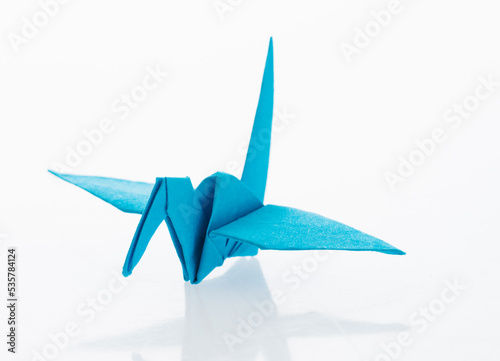 Blue origami paper crane on white background