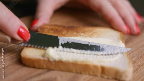Spreading butter over toasted bread by knife