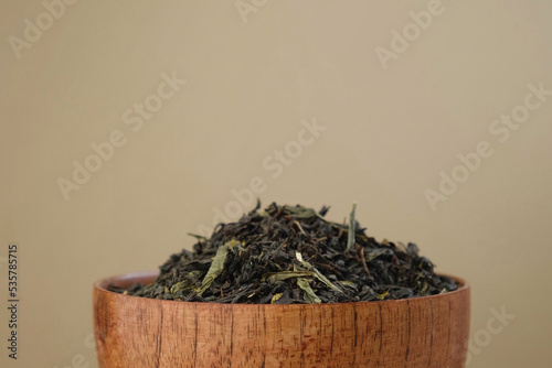 Black Dry Tea Pouring in a Bowl. Pile of Mix Black and Green Tea Leaves. Close Up, Macro. Front View. Texture. Copy Space. Dried Tea is Spinning, Rotating on Turntable. Food and Drink Background photo