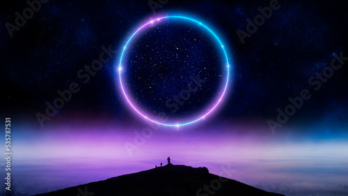 A mystical concept of a man standing on a hill with a glowing neon circle portal in the night sky. With a misty winter landscape in the distance.