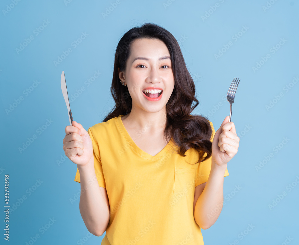 Image of young Asian woman holding knife and fork Image of young Asian woman holding knife and fork