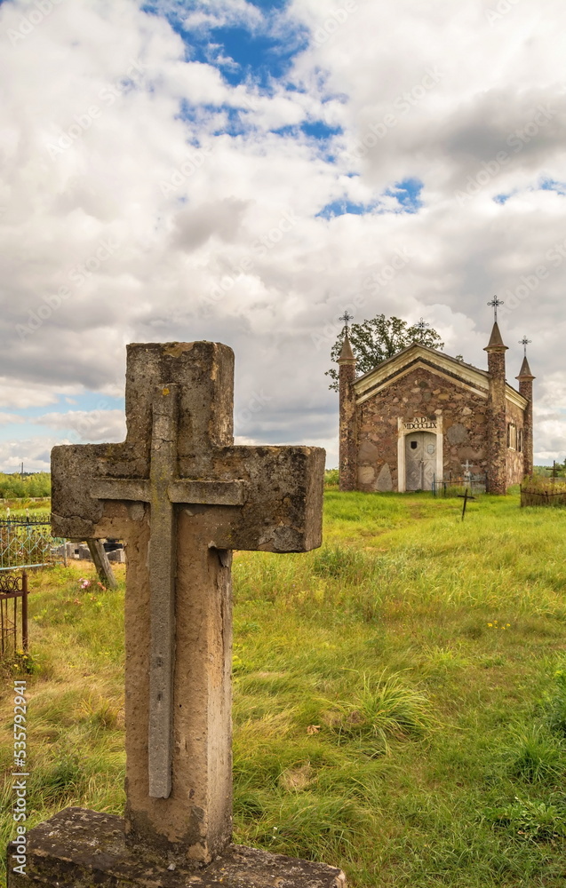 An old stone cross and a Catholic chapel An old stone cross and a Catholic chapel