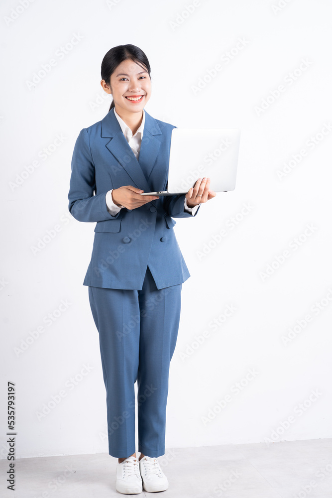 Full length image of young Asian businesswoman holding laptop Full length image of young Asian businesswoman holding laptop